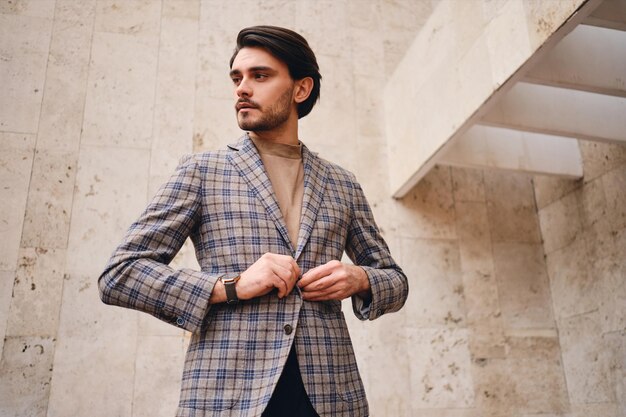 Junger gutaussehender Mann in stylischer karierter Jacke, der nachdenklich im Freien wegschaut