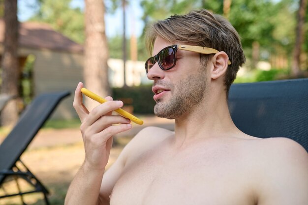 Junger gutaussehender Mann mit einem Telefon in der Hand