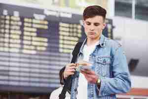 Kostenloses Foto junger gutaussehender mann mit einer tasche auf seiner schulter in eile zum flughafen.