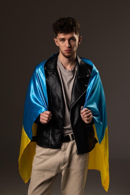 Junger gutaussehender Mann mit Flagge der Ukraine isoliert auf schwarzem Hintergrund