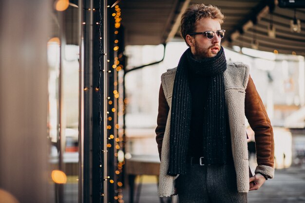 Junger gutaussehender Mann mit Winterkleidung gehend auf Straße