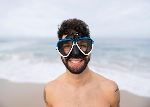 Junger hemdloser Mann am Strand mit Tauchausrüstung