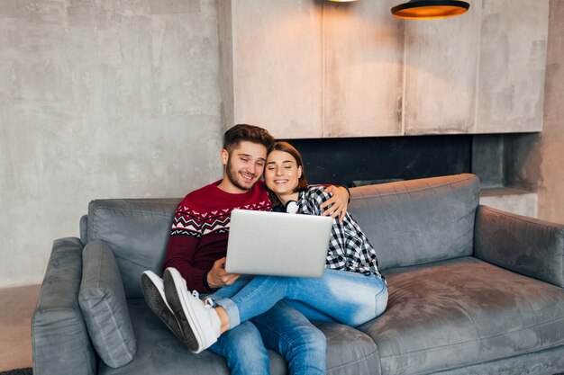 Junger hipster lächelnder mann und frau sitzen zu hause im winter, halten laptop, paar auf freizeit zusammen, studieren online, freiberuflich, glücklich, dating, romantischer abend