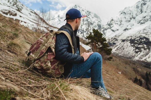 Junger Hipster-Mann, der in den Bergen sitzt