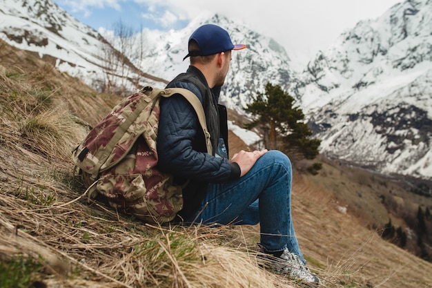 Junger Hipster-Mann, der in den Bergen sitzt