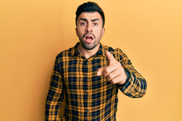 Junger hispanischer Mann in Freizeitkleidung, der unzufrieden und frustriert auf die Kamera zeigt, wütend und wütend auf Sie