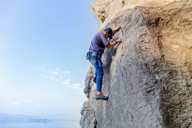 Kostenloses Foto junger hispanischer mann mit einem seil, das sich im klettersport auf dem felsen engagiert?