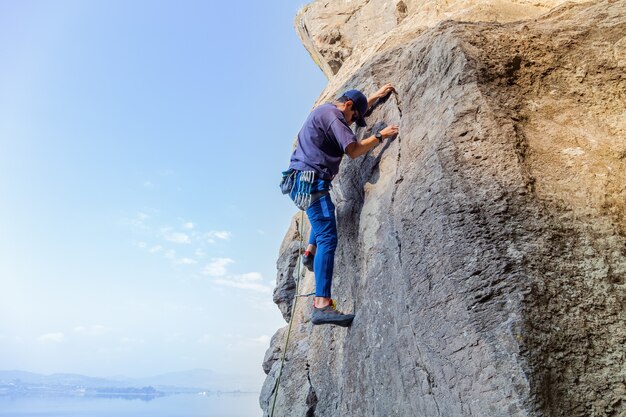 Junger hispanischer Mann mit einem Seil, das sich im Klettersport auf dem Felsen engagiert?