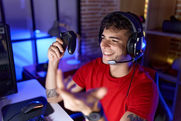 Junger hispanischer Streamer, der Videospiele mit Joystick im Spielzimmer spielt