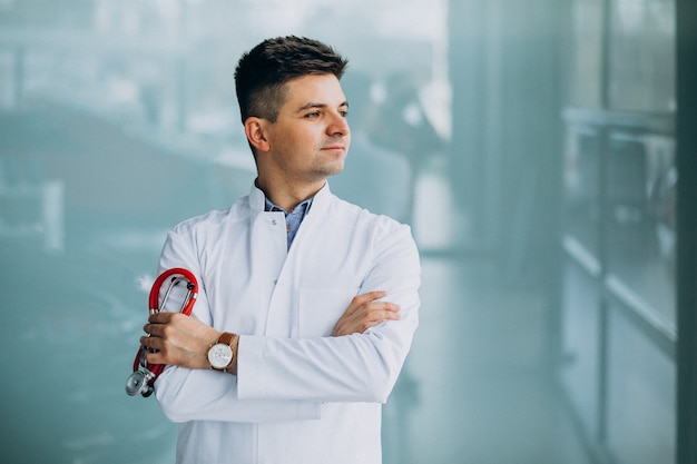 Junger hübscher Arzt in einer medizinischen Robe mit Stethoskop
