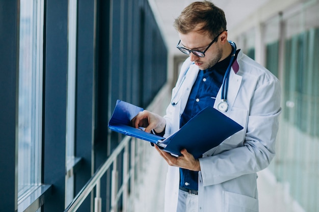 Junger hübscher Doktor, der medizinische Karte liest