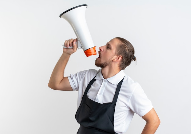 Junger hübscher Friseur, der Uniform spricht, die durch Sprecher lokalisiert auf weißem Hintergrund mit Kopienraum spricht