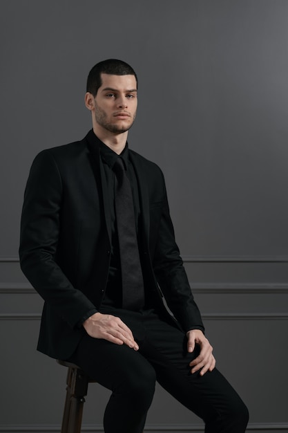 Junger hübscher Geschäftsmann im schwarzen Hemd und im schwarzen Anzug