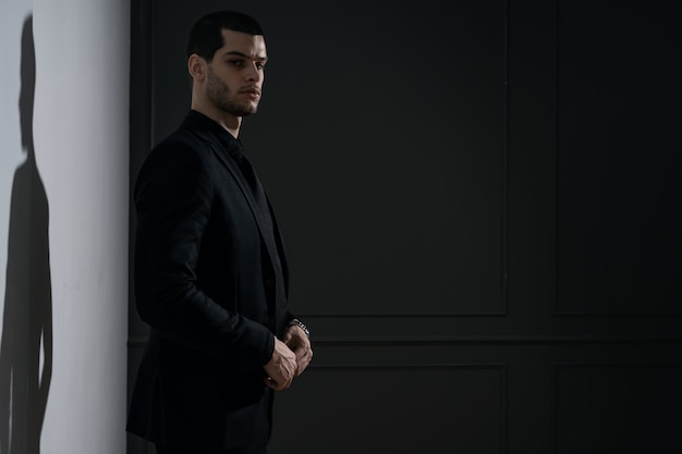 Junger hübscher Geschäftsmann im schwarzen Hemd und im schwarzen Anzug