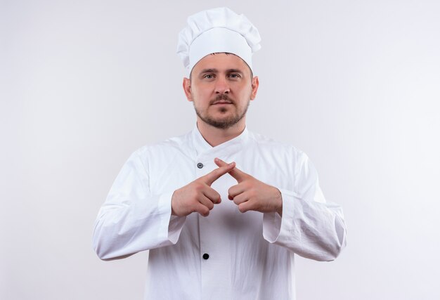Junger hübscher Koch in der Kochuniform gestikuliert, ohne auf weißen Raum isoliert zu schauen