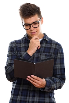 Junger hübscher mann, der buch liest, während er denkt