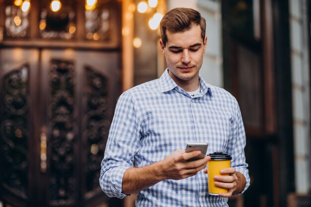 Junger hübscher Mann, der draußen Kaffee trinkt