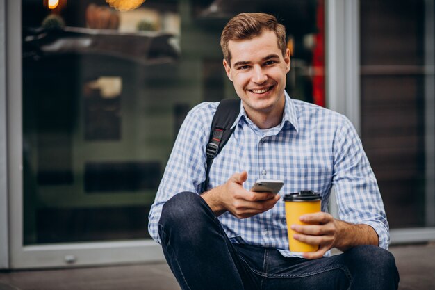 Junger hübscher Mann, der draußen Kaffee trinkt