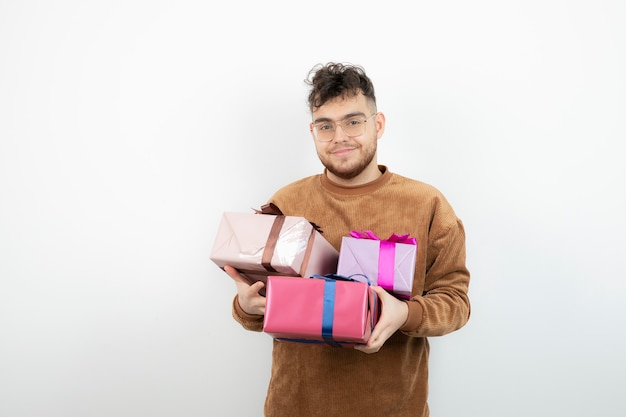 Junger hübscher Mann, der viele Geschenkboxen trägt.