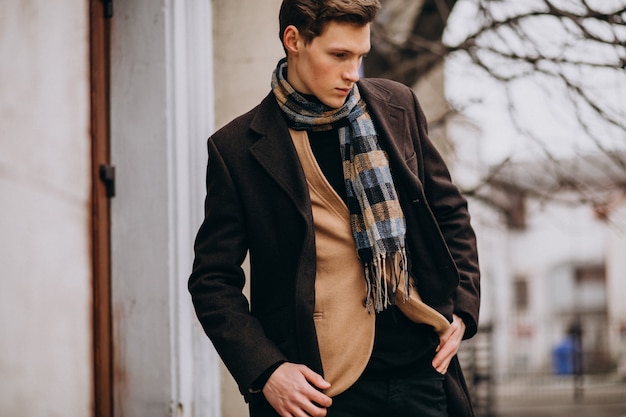 Junger hübscher Mann in einem Mantel außerhalb der Straße