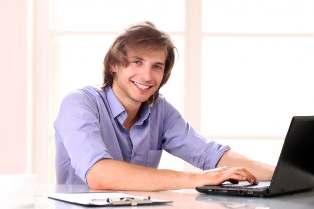 Junger hübscher Mann mit Laptop