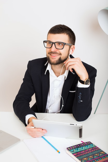 Junger hübscher stilvoller Hipster-Mann in der schwarzen Jacke, die am Bürotisch, Geschäftsstil, weißes Hemd, isoliert, Laptop, Start, Arbeitsplatz, Bleistift, Papierblätter, beschäftigt arbeitet