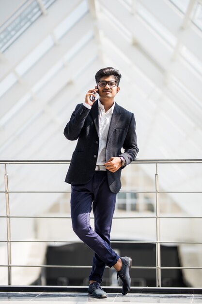 Junger indischer Geschäftsmann an einem Telefon am Telefon