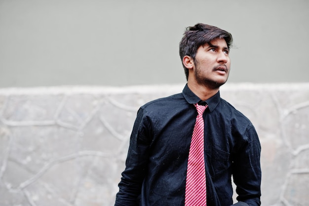 Junger indischer Mann auf schwarzem Hemd und Krawatte posierte im Freien