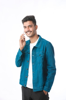 Junger indischer mann, der smartphone verwendet und ausdruck auf weißem hintergrund gibt.
