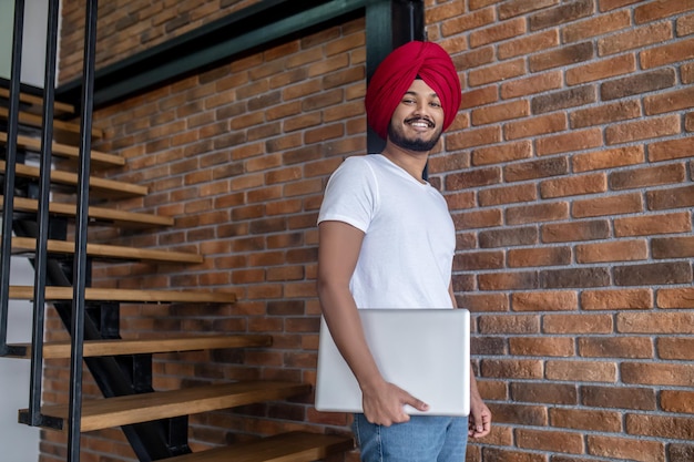 Kostenloses Foto junger indischer mann im roten turban, der auf treppe steht