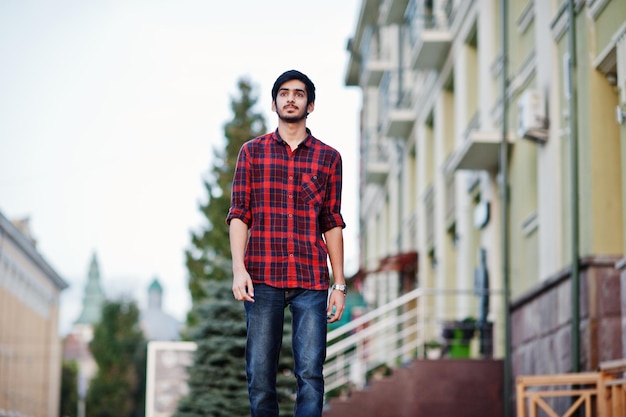 Kostenloses Foto junger indischer studentenmann in rot kariertem hemd und jeans, der in der stadt spazieren geht