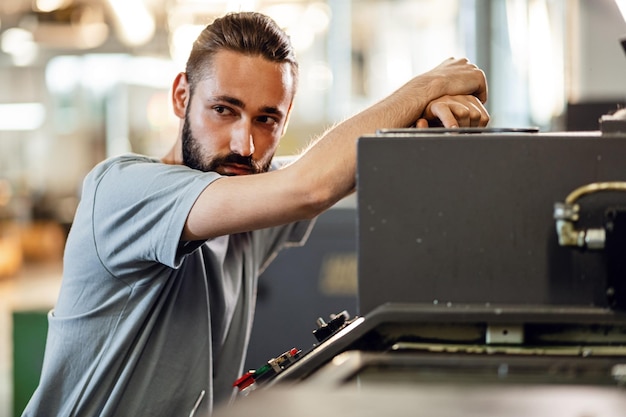 Kostenloses Foto junger industriearbeiter, der eine cnc-maschine bedient und an etwas denkt