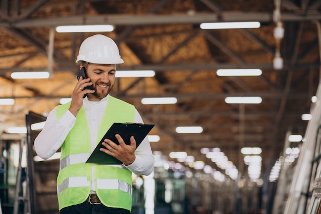 Kostenloses Foto junger ingenieur, der an der fabrik arbeitet, die bestellung am telefon macht