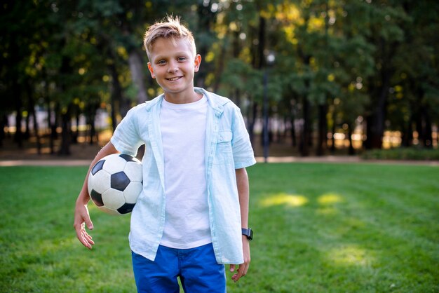 Junger Junge mit der Fußballkugel, die Kamera betrachtet