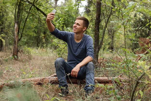 Junger Kerl, der selfie im Wald nimmt