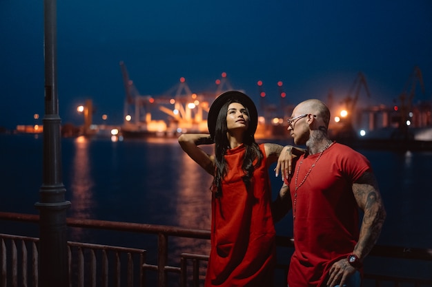 Junger Kerl und schönes Mädchen auf dem Hintergrund des Nachthafens