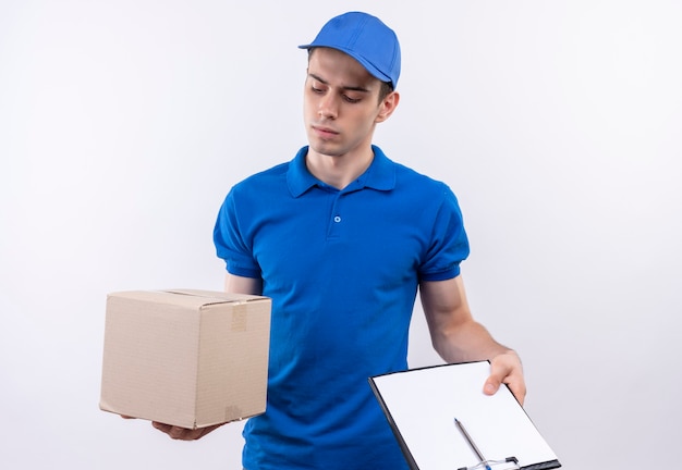 Junger Kurier, der blaue Uniform und blaue Kappe trägt, hält Kisten und Zwischenablage