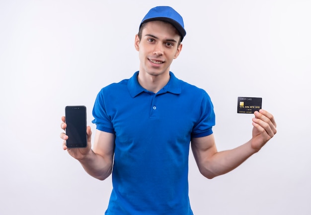 Junger Kurier, der blaue Uniform und blaue Kappe trägt, zeigt Telefon und Karte