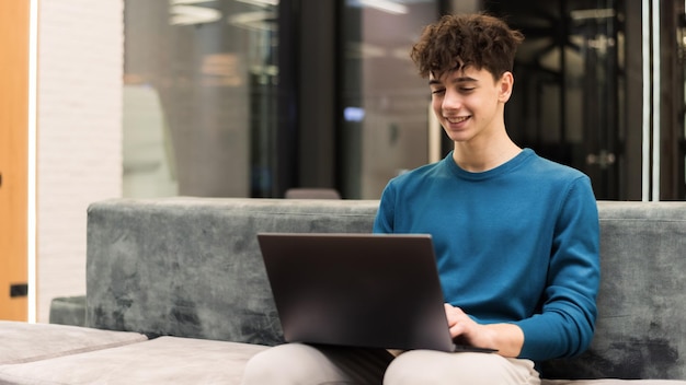 Junger lächelnder Mann, der mit einem Laptop in einem Büro arbeitet
