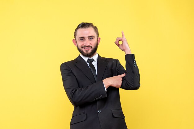 Junger lässiger Mann, der Finger oben mit selbstzufriedenem Gesichtsausdruck zeigt