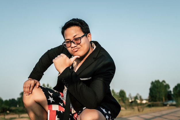 Junger lustiger asiatischer Geschäftsmann, der Hemd und Krawatte mit Shorts und Brille in verrückter und lustiger Weise trägt, kopieren Raum