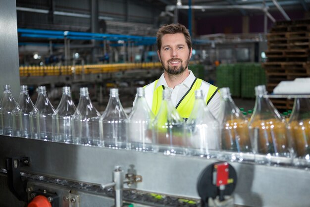 Junger männlicher Arbeiter, der durch Produktionslinie in der Saftfabrik steht