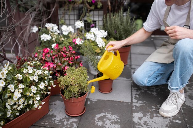 Junger männlicher Florist, der Pflanzen gießt