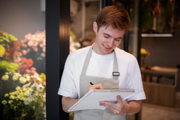 Kostenloses Foto junger männlicher florist, der sich die blumen im shop notiert