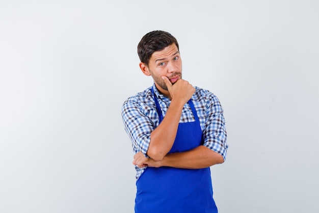 Junger männlicher Koch in einer blauen Schürze und einem Hemd