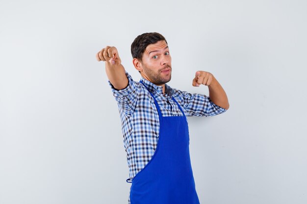 Junger männlicher Koch in einer blauen Schürze und einem Hemd