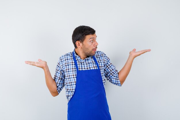 Junger männlicher Koch in einer blauen Schürze und einem Hemd