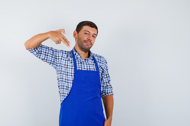 Junger männlicher Koch in einer blauen Schürze und einem Hemd