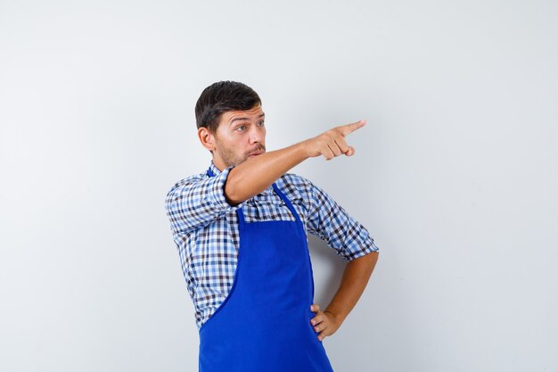 Junger männlicher Koch in einer blauen Schürze und einem Hemd