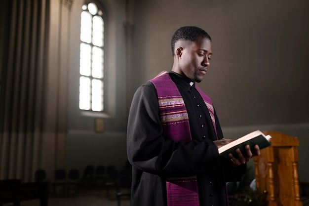 Junger männlicher Priester mit einer Bibel in der Kirche